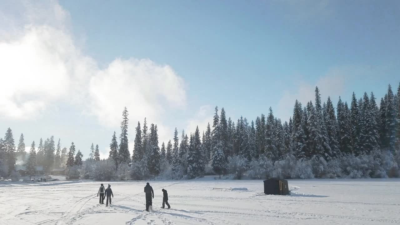 无人机拍摄的一家人在雪地行走后返回度假村视频素材