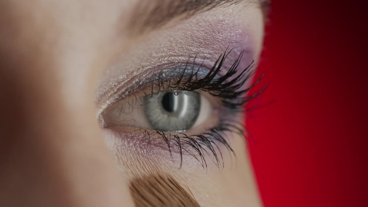 一个女孩用化妆刷在眼睛下面涂抹遮瑕膏的特写。视频素材