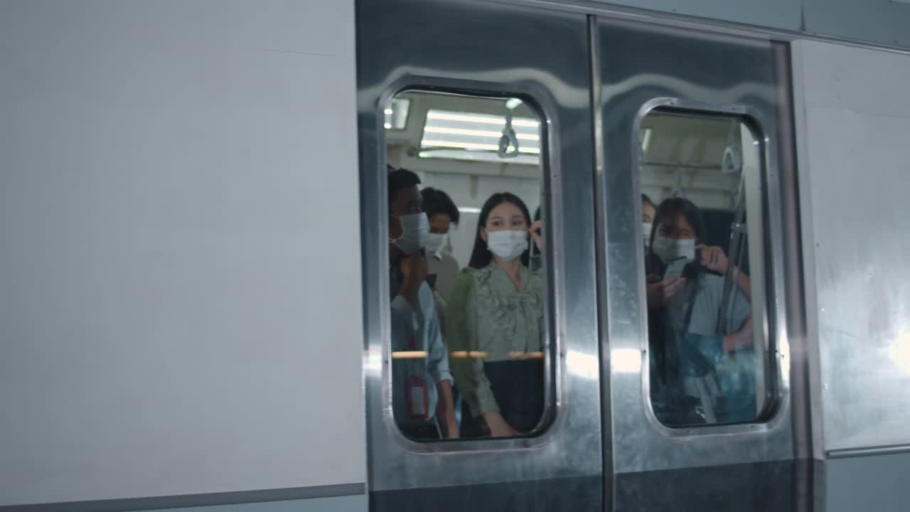 许多戴着防护面罩的乘客在高峰时间进出火车视频下载