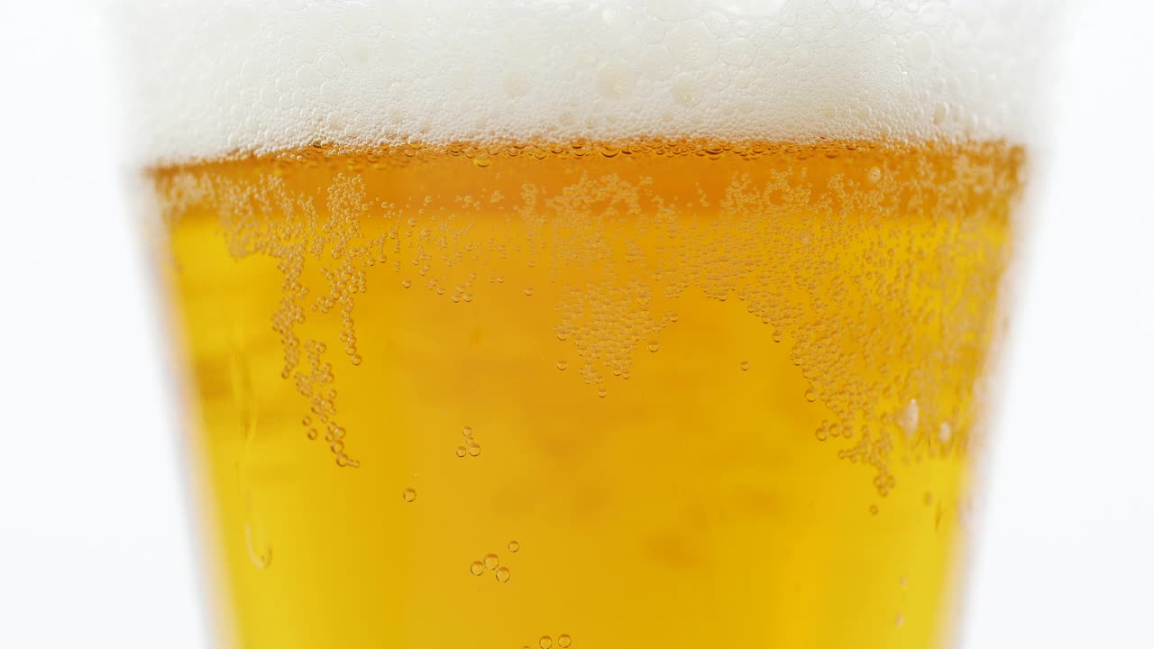 特写把啤酒倒进白色背景的杯子里视频素材