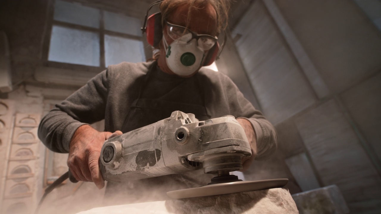 SLO MO LD男性石匠使用电动工具打磨白色石材表面视频下载