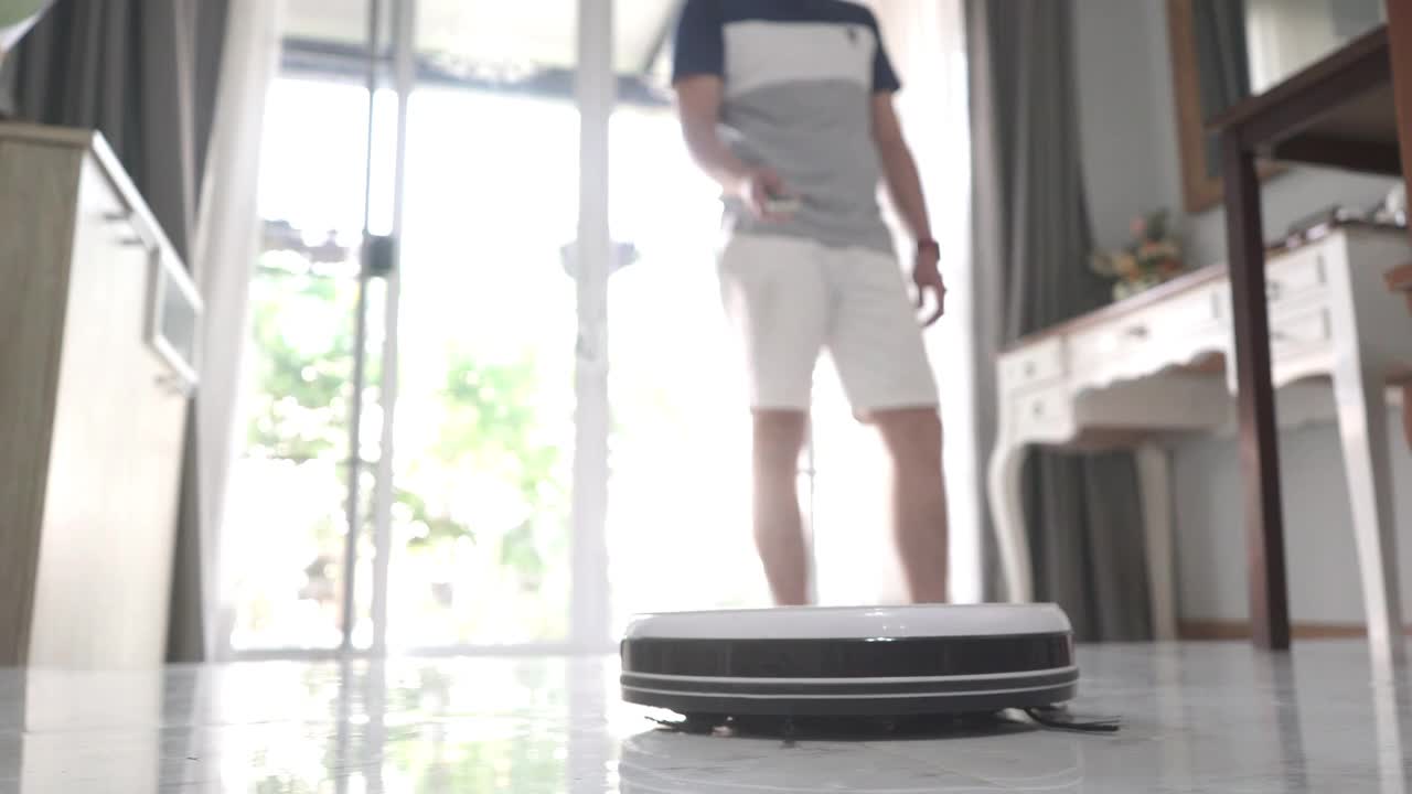 一名男子用智能手机控制家里的智能吸尘器机器人视频下载
