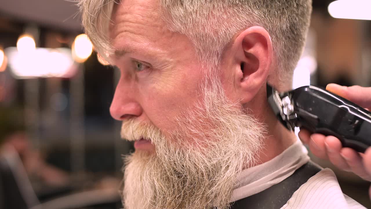 理发师给一个头发花白的大胡子男人理发视频素材