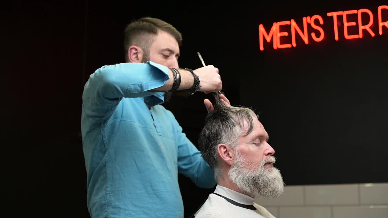 在理发店里，理发师给一位白发苍苍的男子理发视频素材
