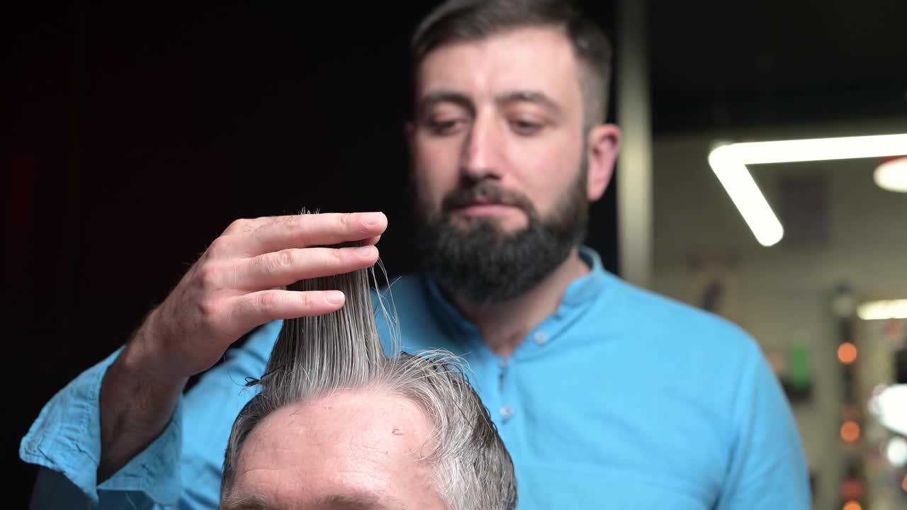 这是一位大师在理发店里拿着客户的头发的作品，特写视频素材