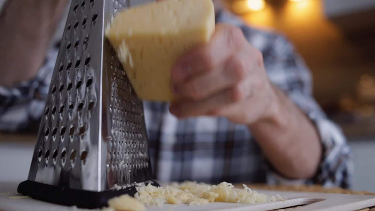 男人在家里磨硬奶酪。慢动作近景视频下载