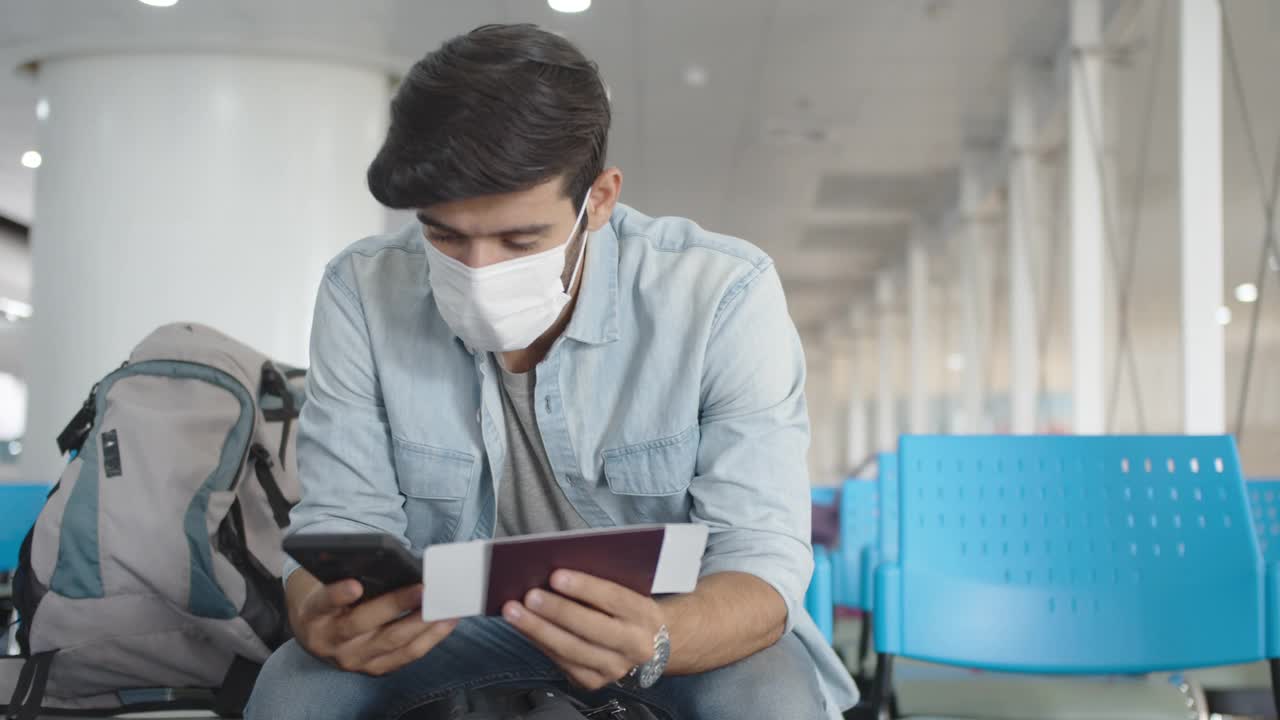 一名白人男子戴着防护面罩，在机场用护照和登机牌自拍视频下载