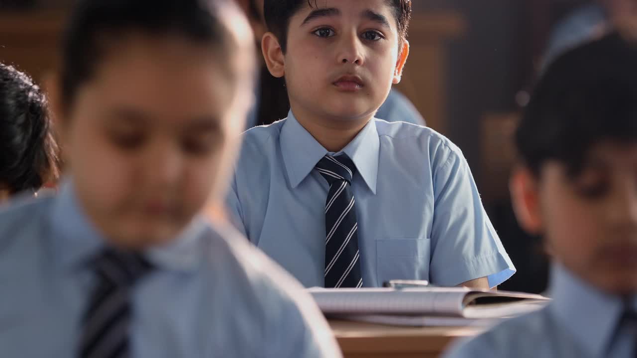 不安分的男孩在教室学习思考的中镜头视频下载