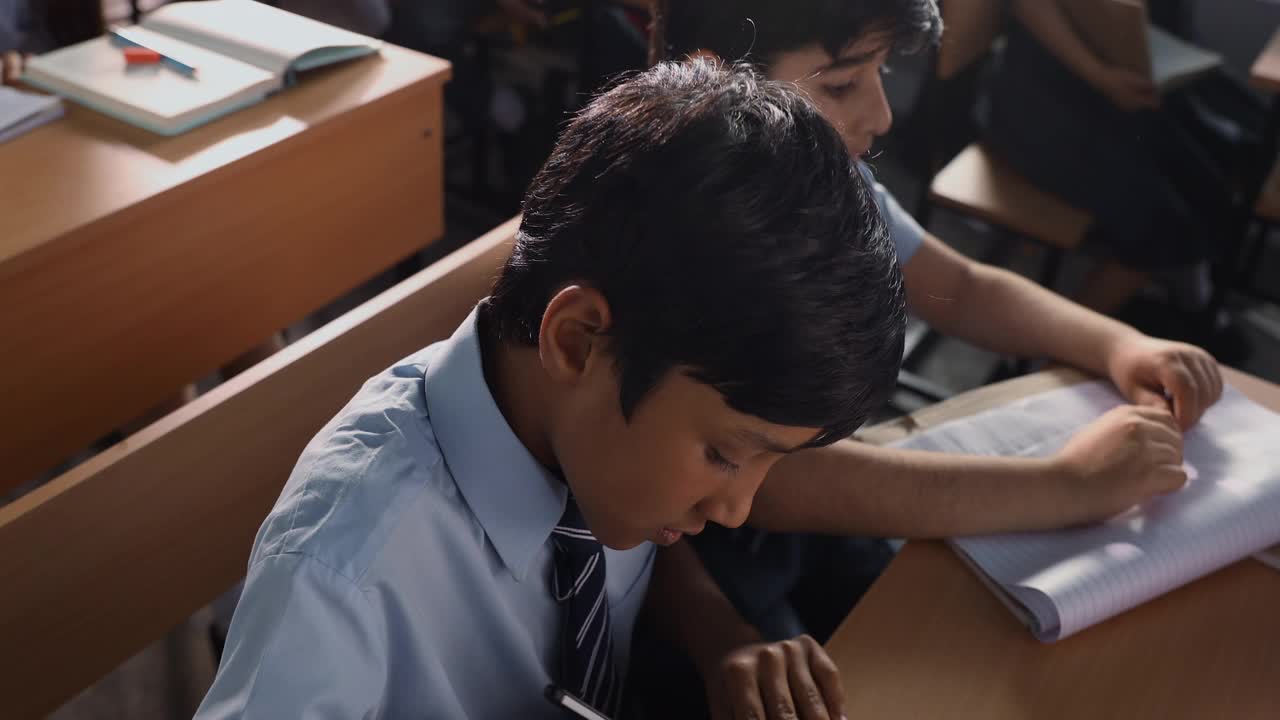 在教室里，一个男孩坐在课桌前，把水洒在他的同学身上视频下载
