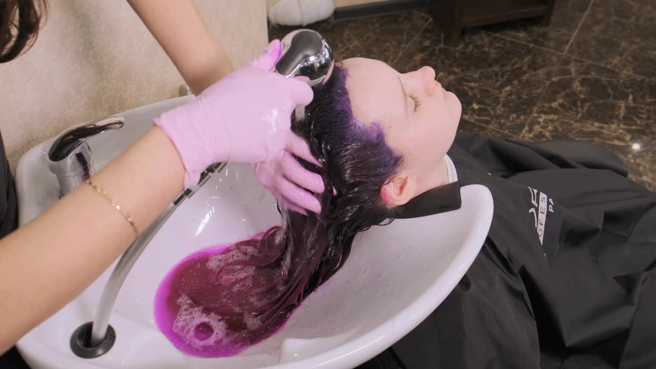 理发师在水槽上给顾客洗紫色的头发视频下载