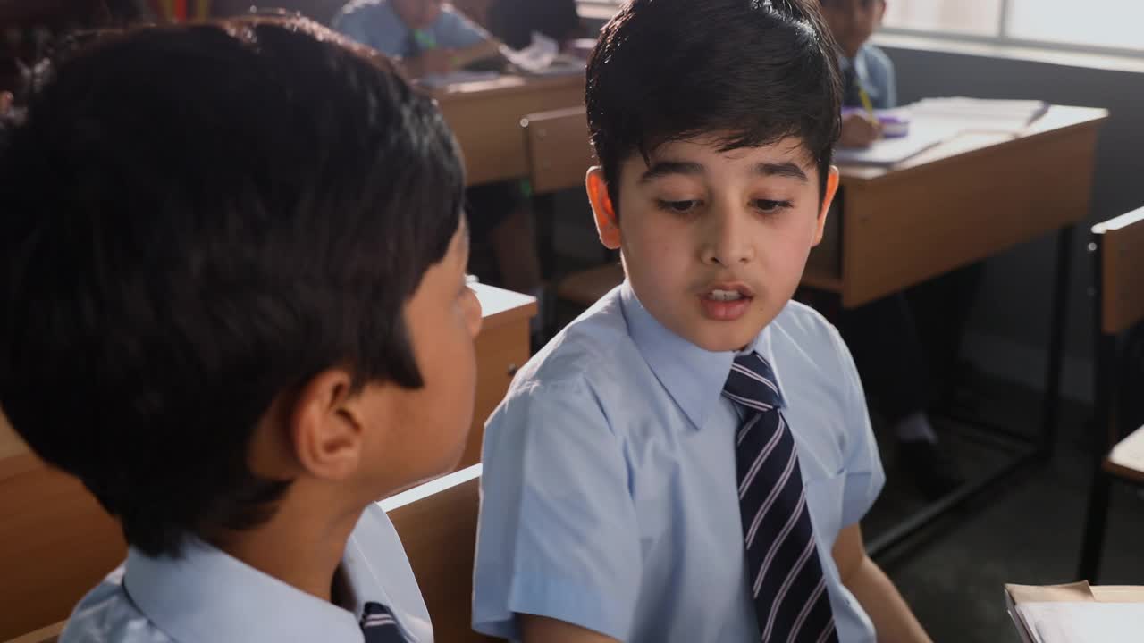 中镜头的男孩捂着耳朵，在教室里向他的同学道歉视频素材