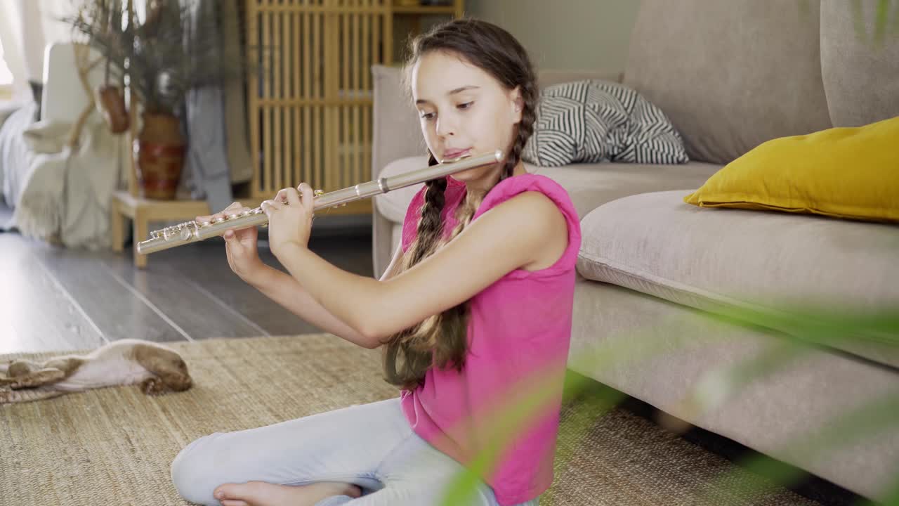 小女孩在家里的地板上吹长笛视频下载