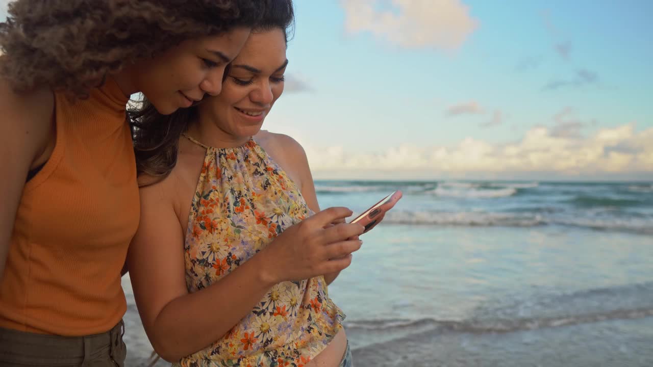 女人在沙滩上走路，用智能手机视频下载