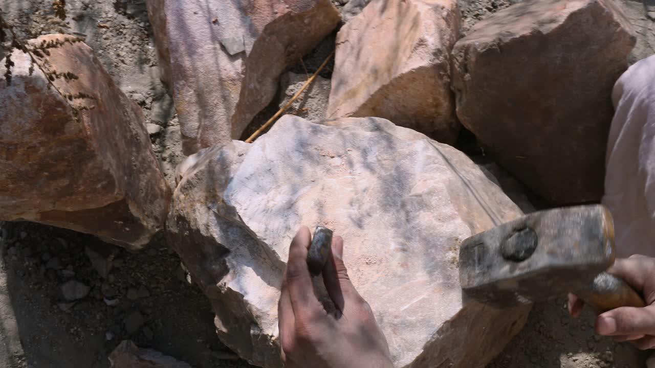 俯视男人的手用锤子和凿子凿石头视频下载