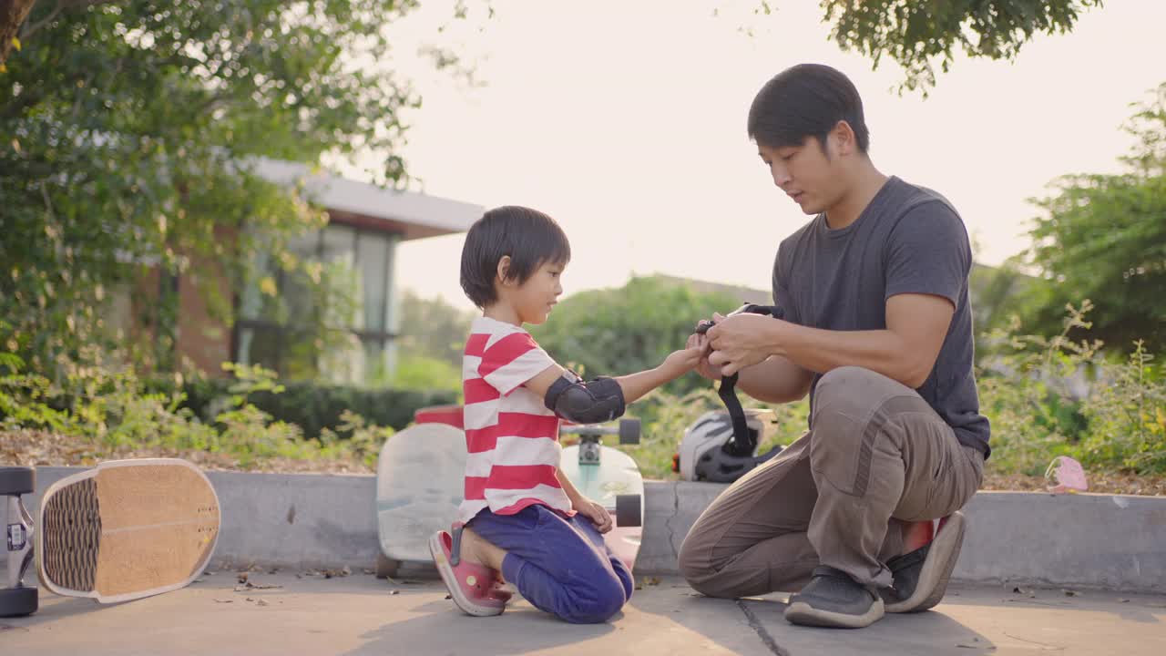 在玩滑板前，父亲帮助儿子戴上护臂。视频素材
