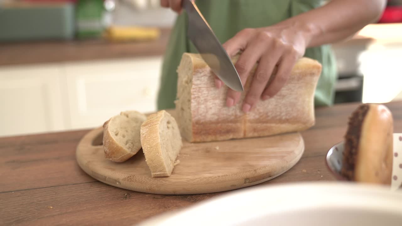 在厨房里用菜刀切面包的妇女视频下载