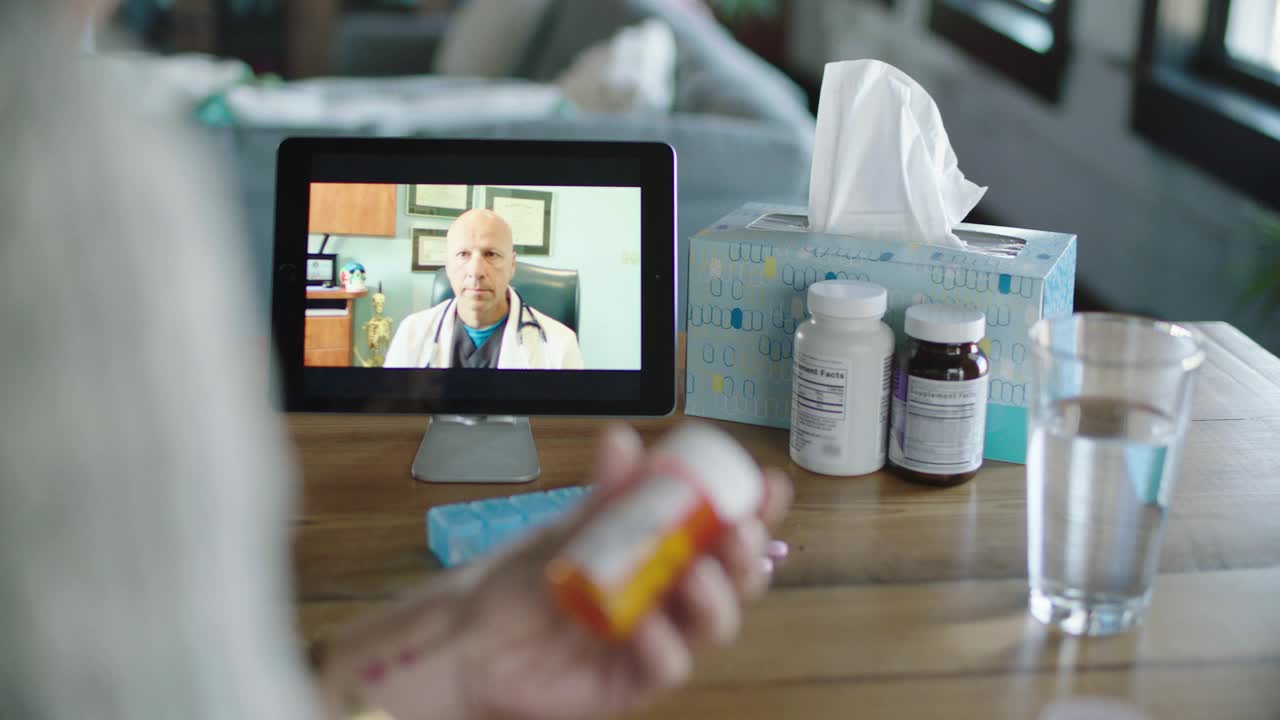 一名年轻女子在与她的医生视频通话时检查她的新药丸视频素材