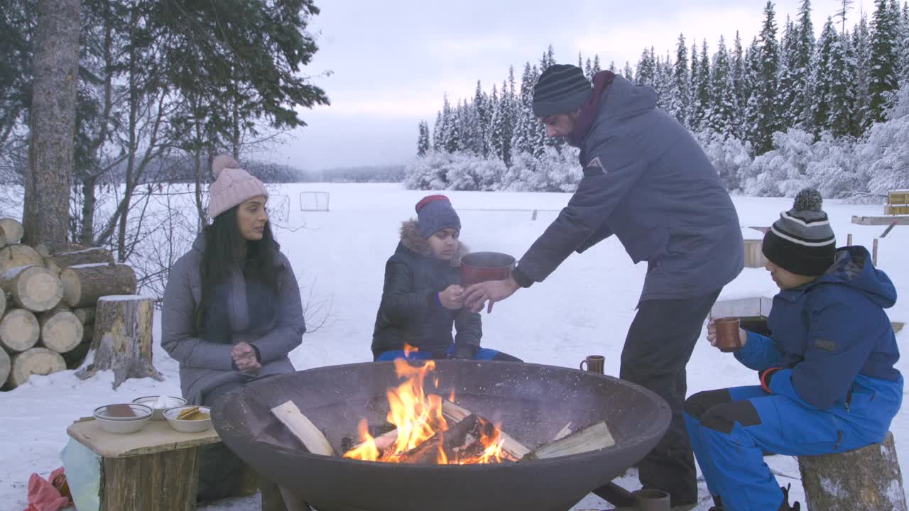 一家人围坐在冬天的炉火旁，爸爸给儿子倒热巧克力视频下载