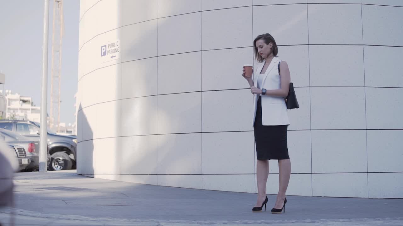 女商人在户外工作时喝咖啡，看智能手表视频下载