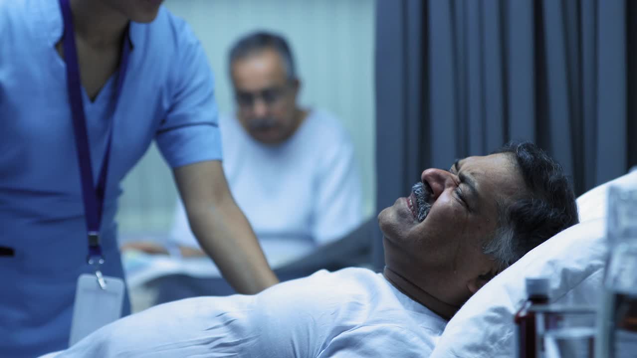 护士安慰躺在病床上哭泣的成年男子，背景是老年男子在看报纸视频下载