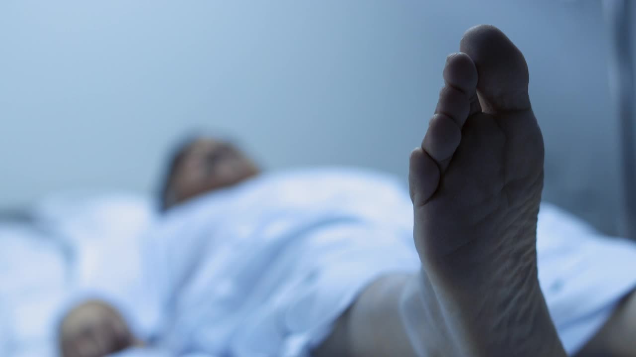 中等拍摄的生病的成熟男子移动腿时，躺在医院的床上视频下载