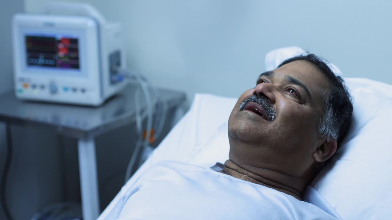 中等拍摄的生病的成熟男子哭泣和说话，而躺在医院的床上视频素材