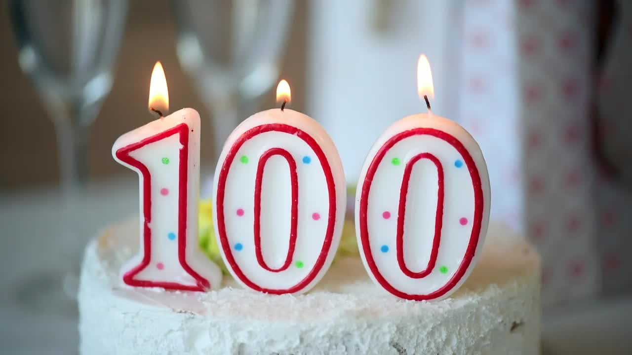 生日蜡烛作为数字一百在桌子上的甜蛋糕，百岁生日视频下载