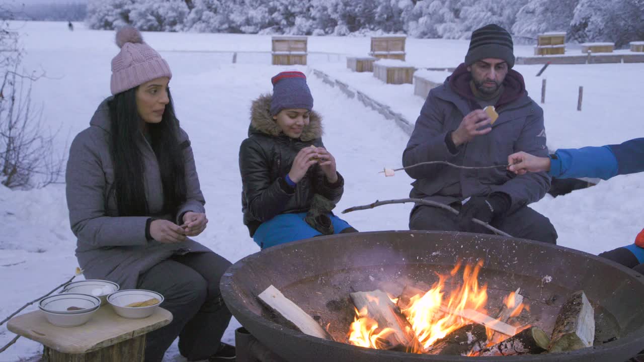一家人围坐在雪地里的篝火旁享用饼干视频下载