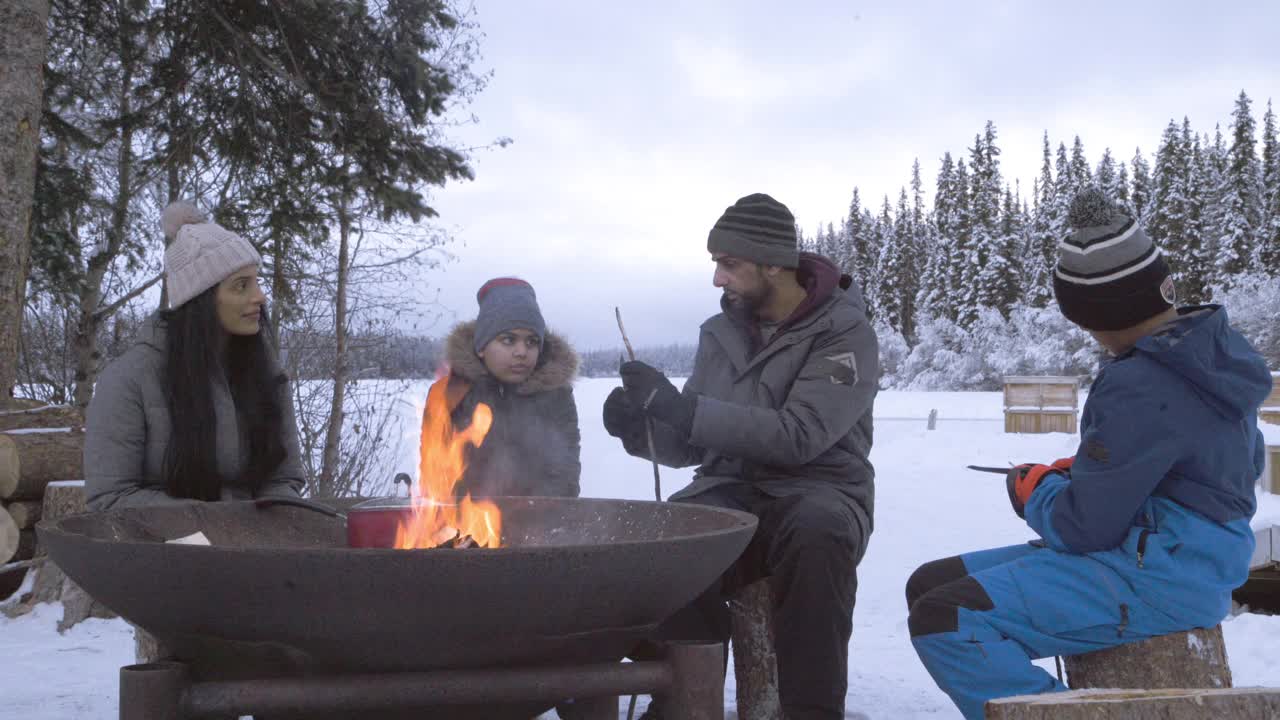 一家人欢声笑语，削木棍在冬天的火上烤棉花糖视频下载