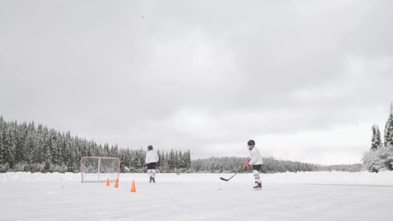 两兄弟在结冰的湖面上练习冰球视频下载