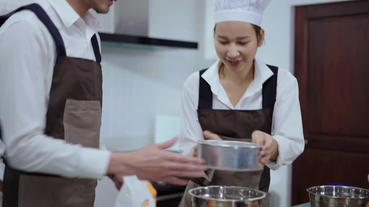 一对年轻夫妇筛面粉做面团做面包房视频下载
