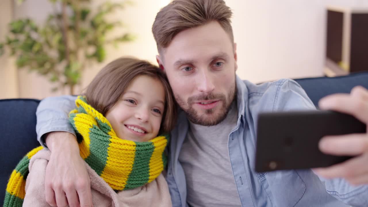 快乐的女孩和父亲通过智能手机应用自拍，一起玩得很开心视频素材
