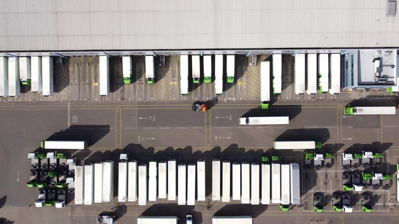 配货仓库鸟瞰图，装卸区设有货车。从左到右的轨迹。视频下载