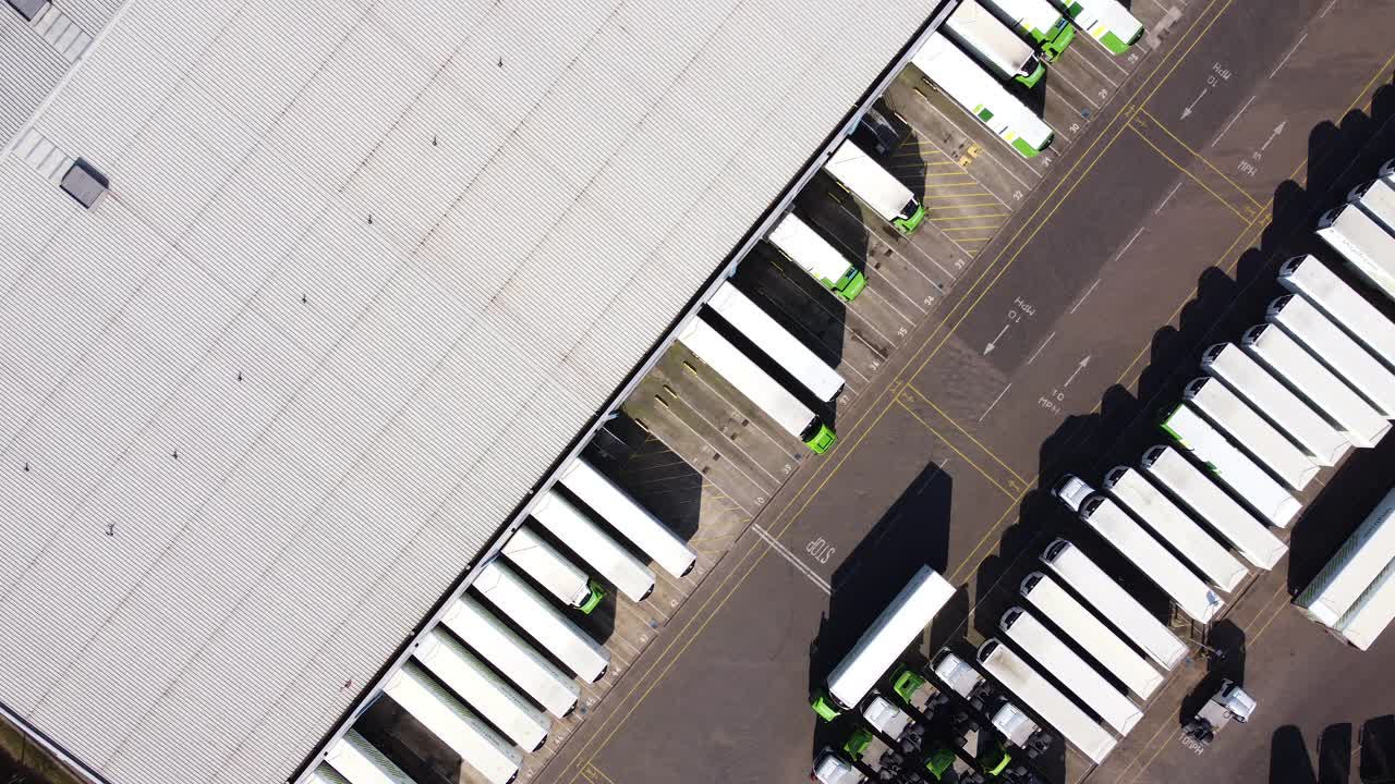 配货仓库鸟瞰图，装卸区设有货车。从左到右的轨迹。视频素材