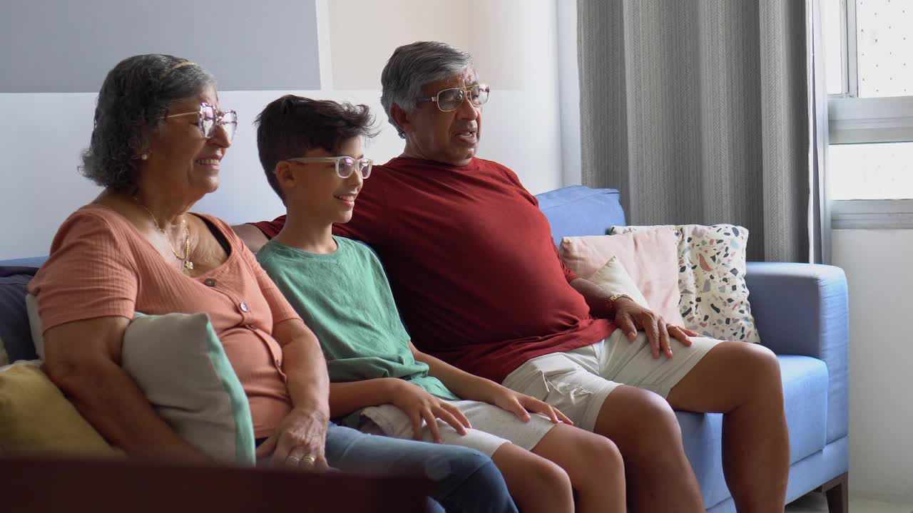 爷爷奶奶和孙子在家里看电视视频素材