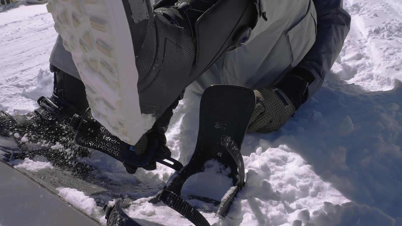 滑雪板绑在一块滑雪板上，坐在山坡的雪地上视频下载