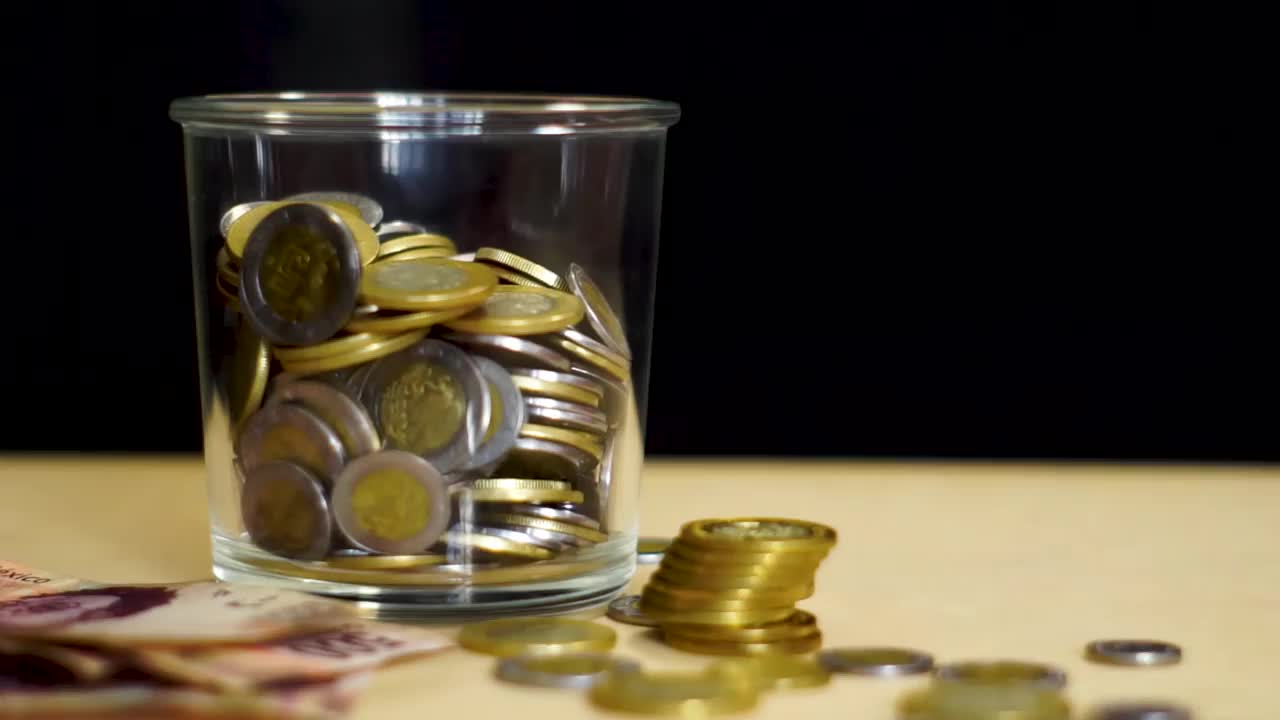 黑色背景的玻璃罐中的墨西哥硬币视频素材