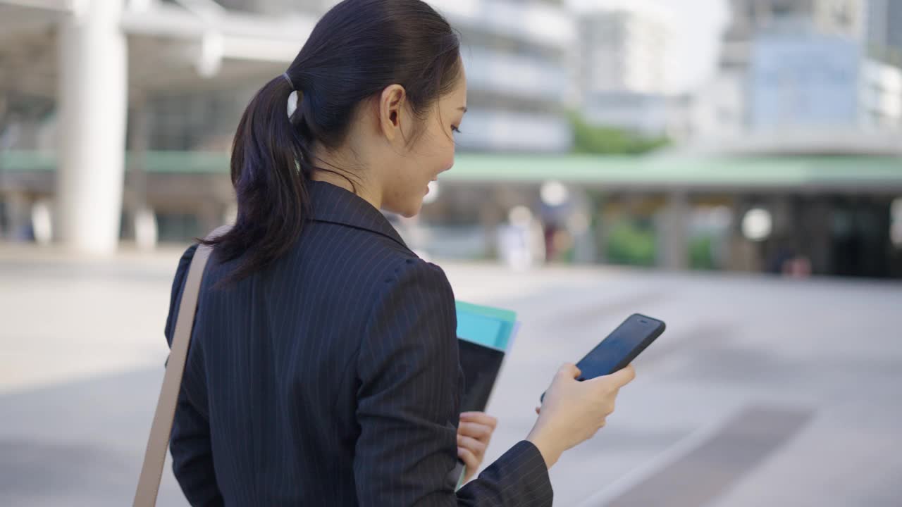 在城市里带着智能手机走路的女商人，通勤上班视频素材