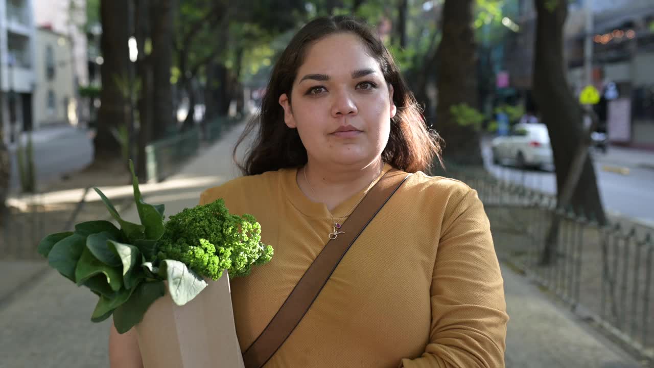 拉丁妇女的肖像，拿着装满蔬菜的可重复使用的袋子视频下载
