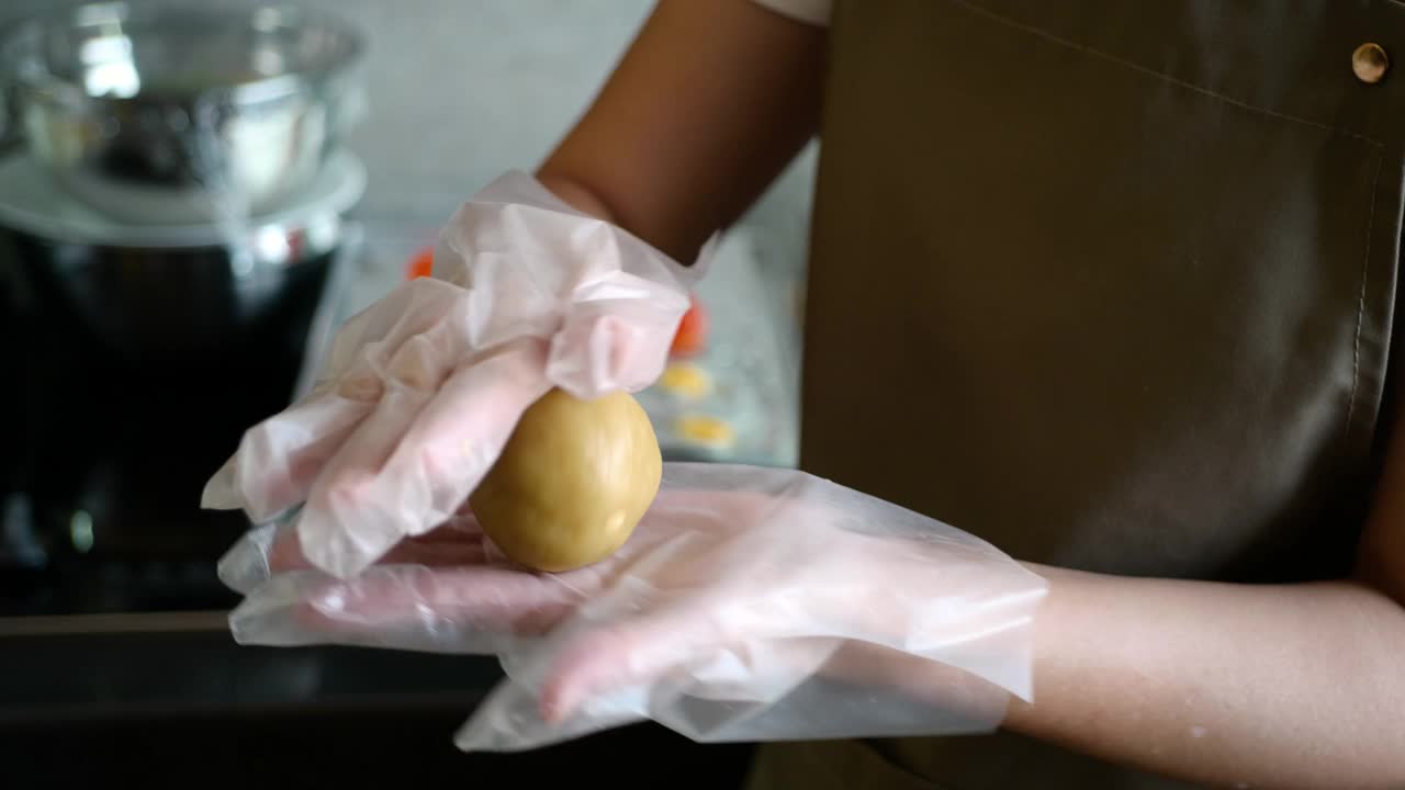 亚洲妇女耳环手套和在厨房做月饼面团视频素材