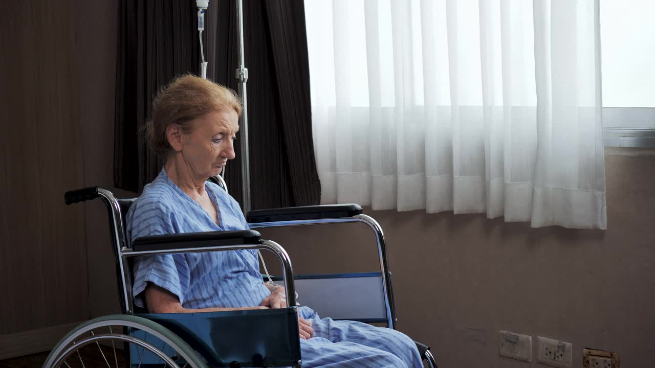 残疾老年妇女独自坐在轮椅上在医院。视频下载