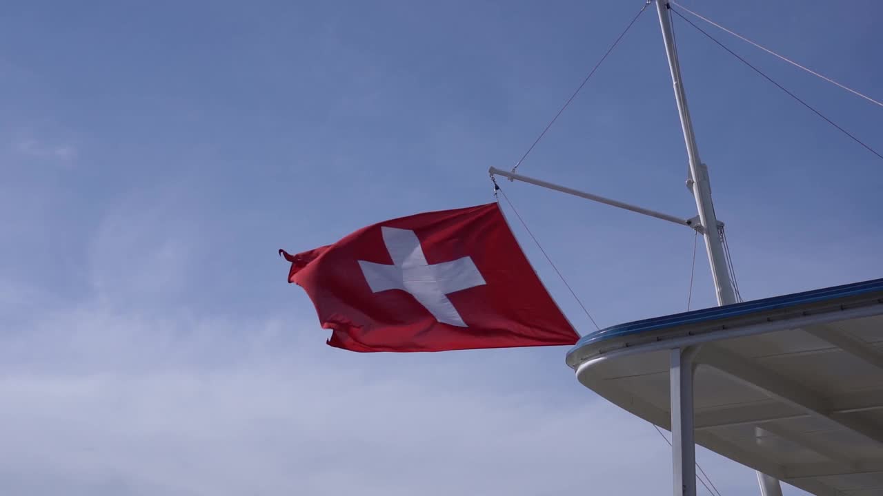 瑞士苏黎世湖上的一艘船在风中飘扬着瑞士国旗。视频素材