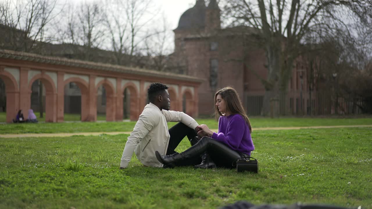 快乐的跨种族情侣互动在公园外微笑和约会视频下载