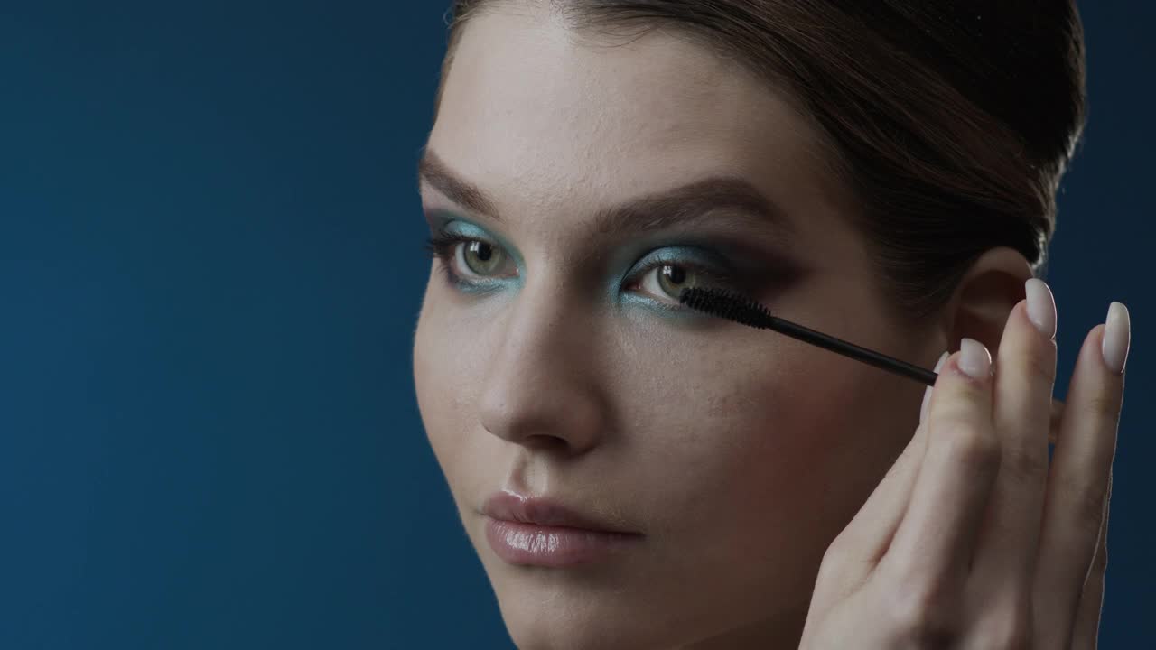 化妆的步骤。一个女孩的特写与绿色的眼睛使用刷睫毛膏。视频下载