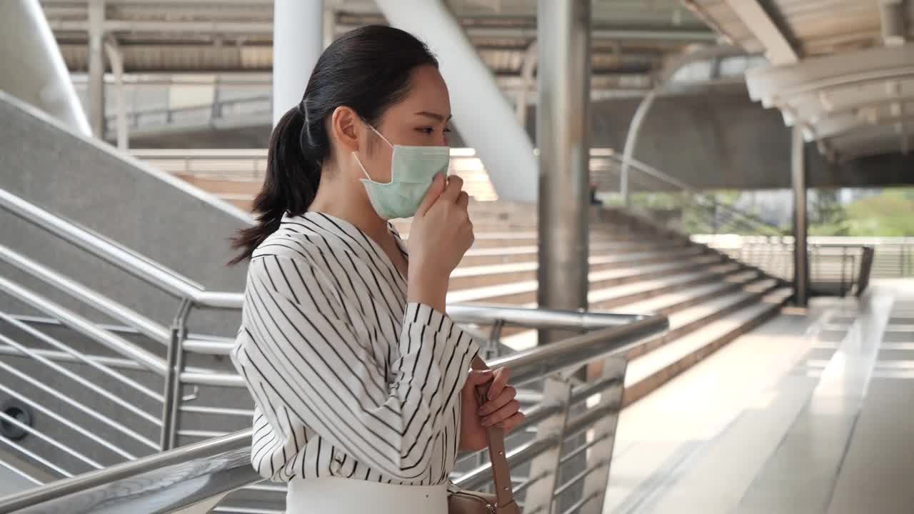 亚洲女商人戴医用口罩在公共场合喉咙痛咳嗽。医疗保健、空气污染和冠状病毒爆发的概念视频下载