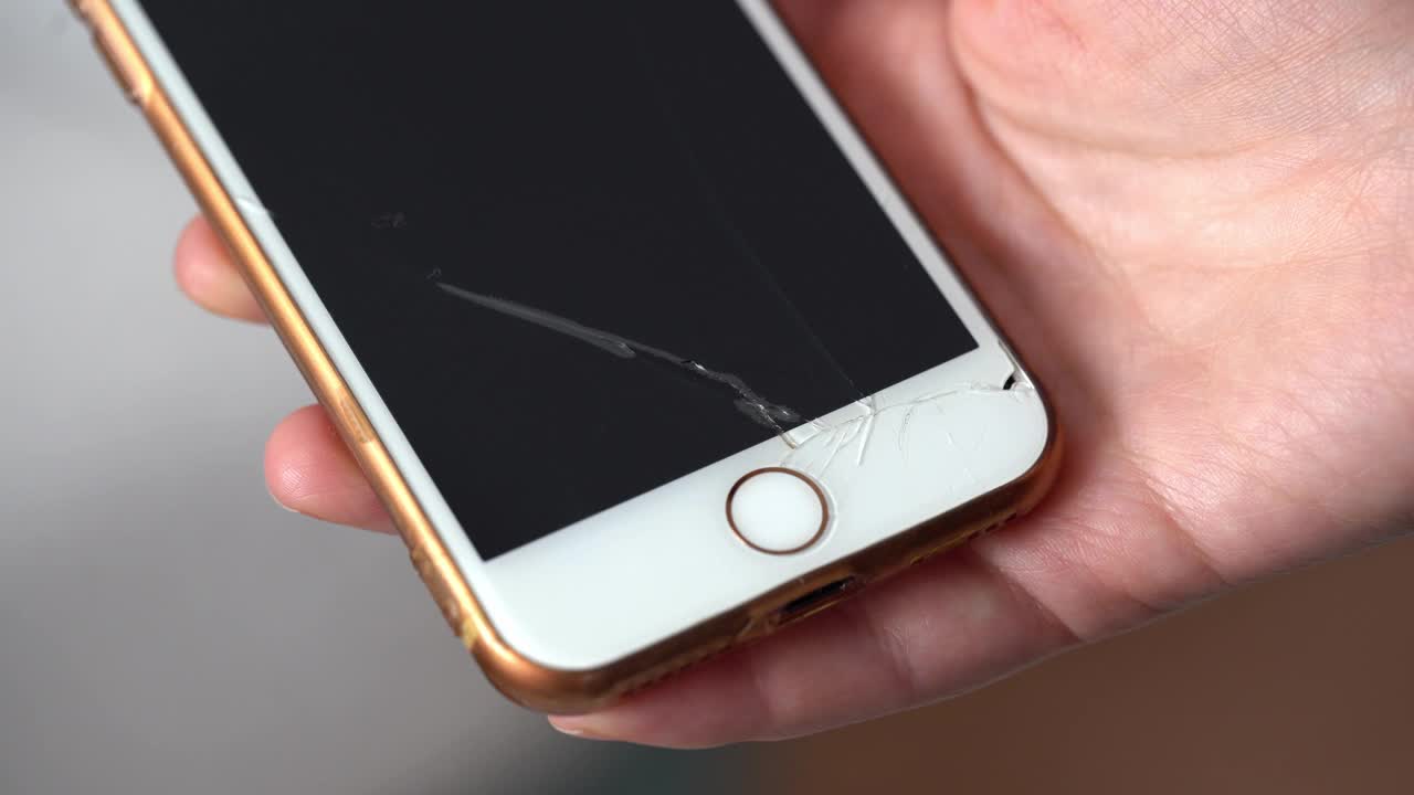 一名女子拿着破碎屏幕的智能手机。视频下载