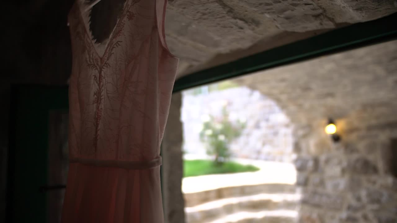 一件漂亮的淡粉色婚纱挂在入口上方，进入一个舒适的房间，有绿色的门视频下载