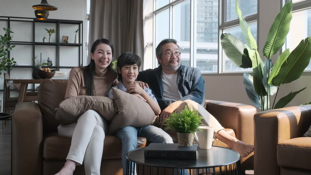 幸福的亚洲家庭一起在客厅的沙发上看电视。家庭家居概念视频素材