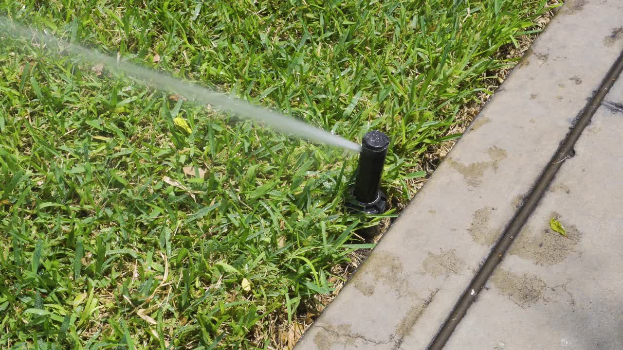 一个自动草坪洒水器在街道上的公园移动的特写视频素材