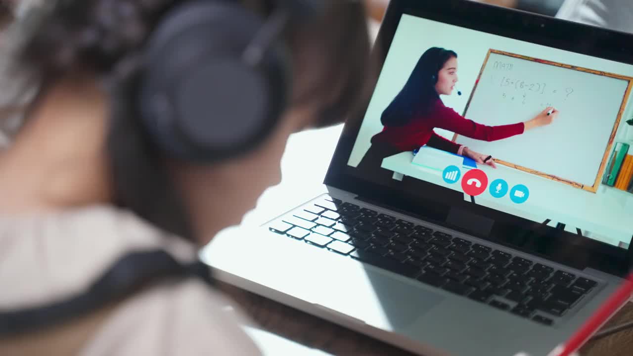 由于冠状病毒大流行，亚洲小女孩通过数字远程互联网会议从学校老师那里学习在线课程。孩子望着电脑屏幕上那个正在教书的女人视频素材